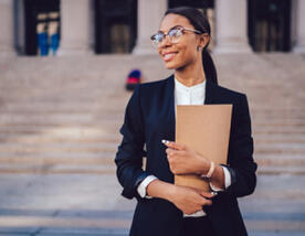 Grad student on courthouse steps holding business folders